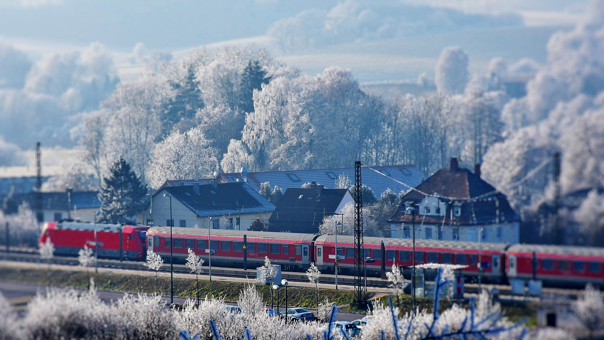Ein Zug fährt durch das verschneite Bayern.